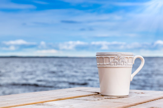 Summer view - cup against horizon with blue sky and water.
