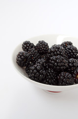 Blackberries in a white plate on a white background