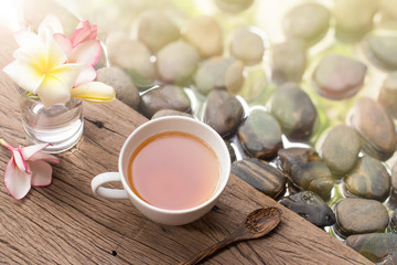 hot tea in white cup with flowers on wooden pebble stone water b