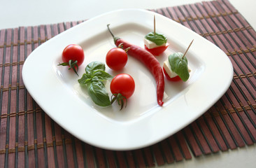 Fresh cherry tomatoes and chili on white plate.