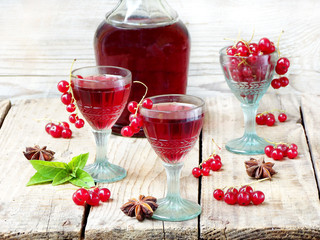 homemade red currants liquor on a wooden background