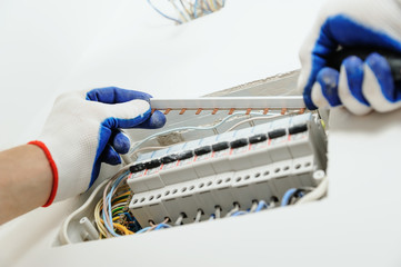 Electrician installing an electrical fuse box .