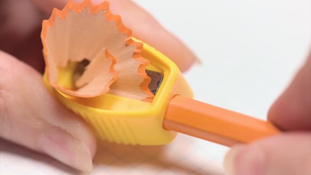 Close up of female hands sharpening a pencil on white background