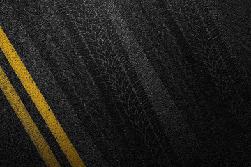 Level asphalted road with a dividing yellow stripes and tyre tracks. The texture of the tarmac, top...