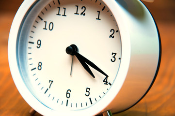 White alarm clock isolated on wooden background