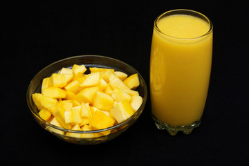 Fresh mango juice in a glass with slice over black background