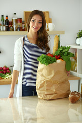 Young woman holding grocery shopping bag with vegetables