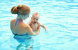 mother teaching baby swimming pool