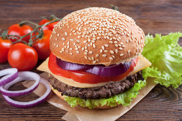 Homemade cheeseburger on brown wooden surface.