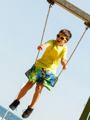 Boy playing swinging by swing-set.