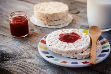 Round rice cakes as breakfast or snack with sweet strawberry jam and a glass of milk.