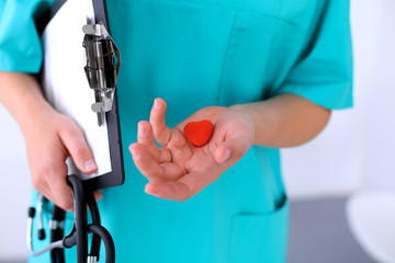 Female surgeon doctor with stethoscope holding heart.