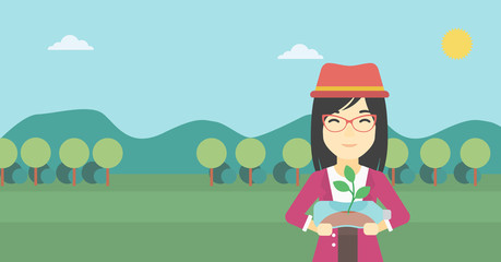 Woman holding plant growing in plastic bottle.