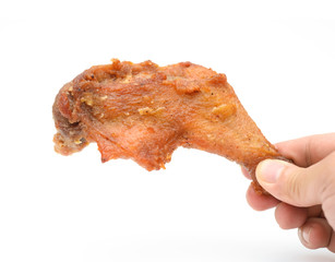 hand holding a fresh grilled chicken leg on a white background