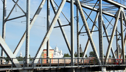 Naklejka premium Railway metal bridge perspective view. Russian monastery on backdrop