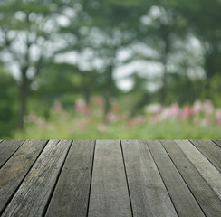 Empty old wood floor with blur of pink flower and tree in public