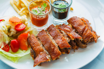 Eisbein with vegetables baked with sauce on the plate.