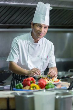 Portrait of a smiling male chef with cooked food standing in the kitchen, Chef Thailand