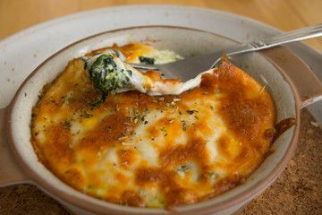 Baked spinach with cheese and fork in café
