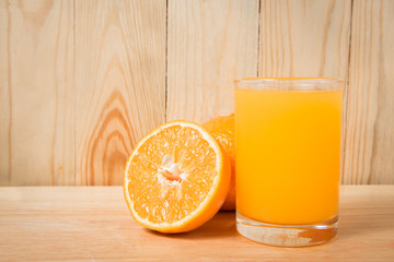 orange fruit and a cup of orange juice on a wooden block