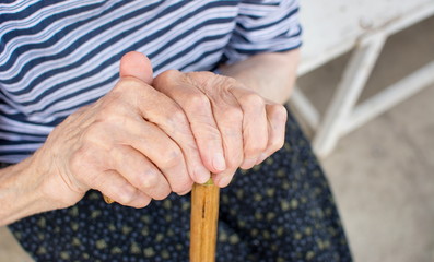 Old woman hands holding a walking cane