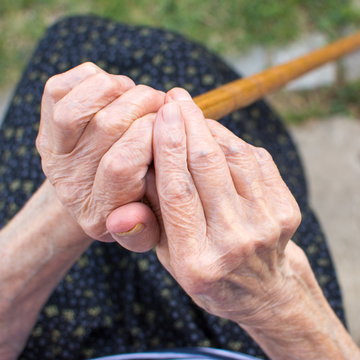 Old woman hands holding a walking cane