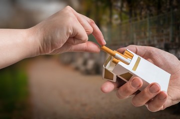 Hand is taking cigarette from cigarette pack an accepting an offer.