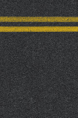 Fototapeta premium Level asphalted road with a dividing yellow stripes. The texture of the tarmac, top view.