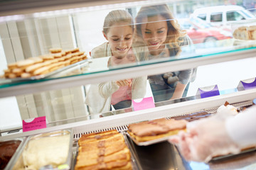 Daughter and mother choose sweets in candy store