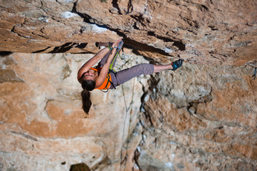 Girl climber climbs on rock.