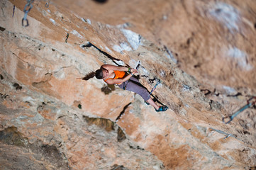 Girl climber climbs on rock.