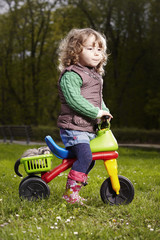 Little girl posing on three-wheeler with ferret