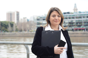 Fototapeta premium Portrait of business woman holding clipboard and smartphone.