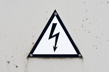 Old and dirty high voltage sign on white metal plate