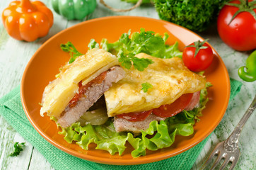 Pork chop with tomatoes, potatoes and cheese in a cut
