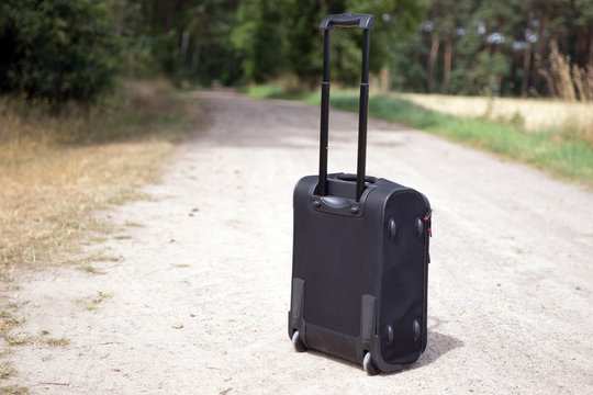 Hand luggage suitcase on the dirt road