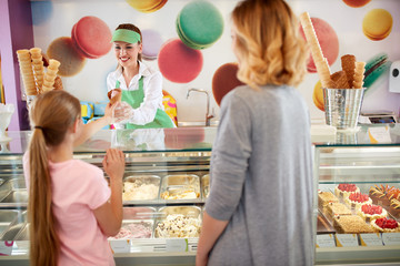 Seller in bakery gives ice cream to girl