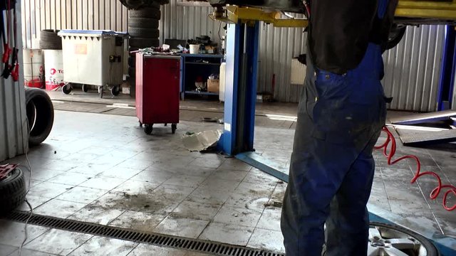 Auto mechanic working at auto repair shop. tilt down.