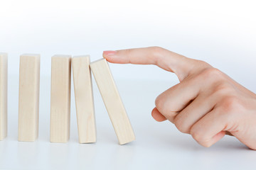 Human hand starting a domino effect concept with wooden blocks