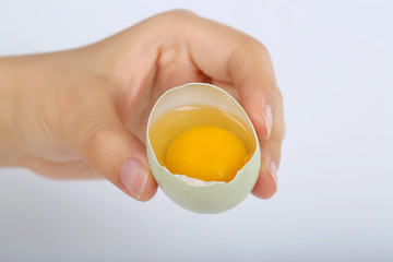 Hand with egg and closeup of yolk
