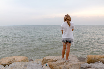 woman stand on the rock see sea eveing