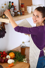 Young woman standing in her kitchen near desk