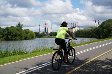 Fototapeta premium woman on bike rides along the bike path, rear view