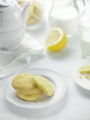 Lemon cookies and milk on white table, beautiful dishes