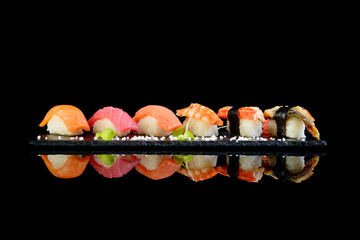 Assorted sushi on a black background with reflection