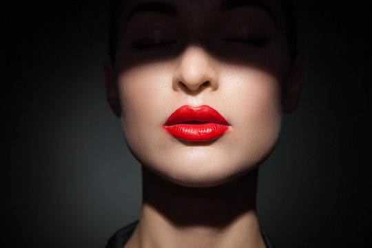 Beautiful model with bright red lips and face half covered in shadow