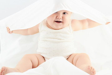 Fototapeta na wymiar smiling baby girl under the white blanket. little funny child.newborn