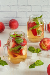 Homemade lemonade with peaches and mint leaves.