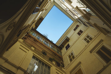 Obraz premium Cozy historic courtyard in the old town of Rome. Windows with shutters vintage, a small balcony and blue summer sky above.