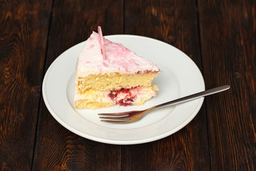 Pink cake slice on dark wooden background